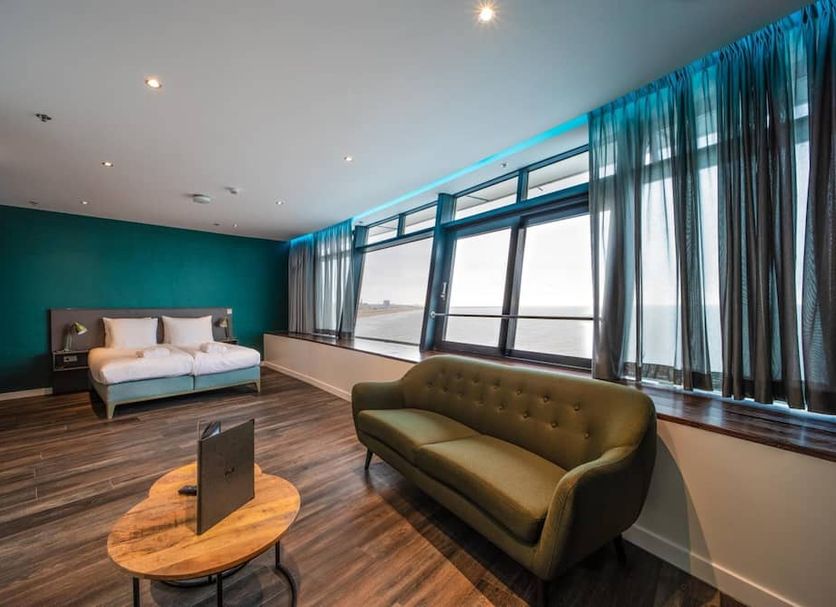 De Pier Suites in The Hague guest room with sofa, bed, and large windows overlooking the sea