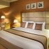 City Seasons Al Hamra Hotel in Abu Dhabi guest room with king bed, armchairs and warm lighting