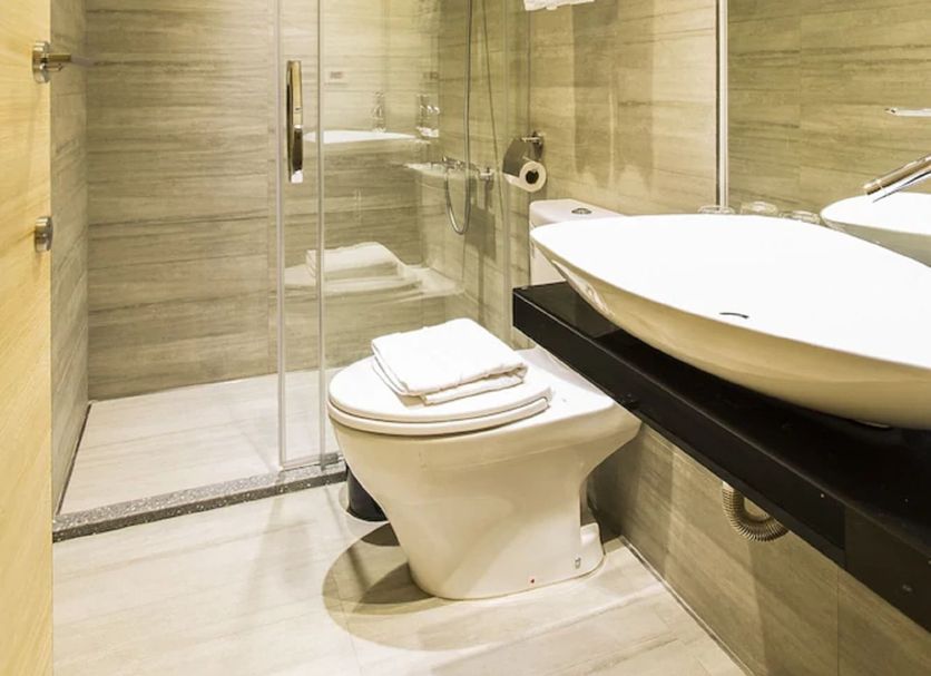 The Tree House in Kaohsiung City bathroom with glass shower, toilet, sink, and towel rack