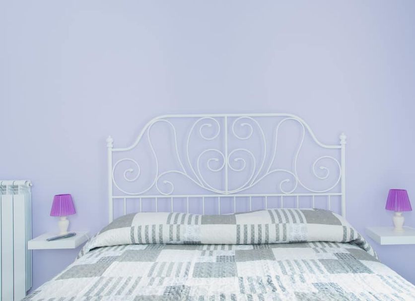 Sfumature Partenopee Naples room with white wrought-iron bed, striped bedding and purple lamps