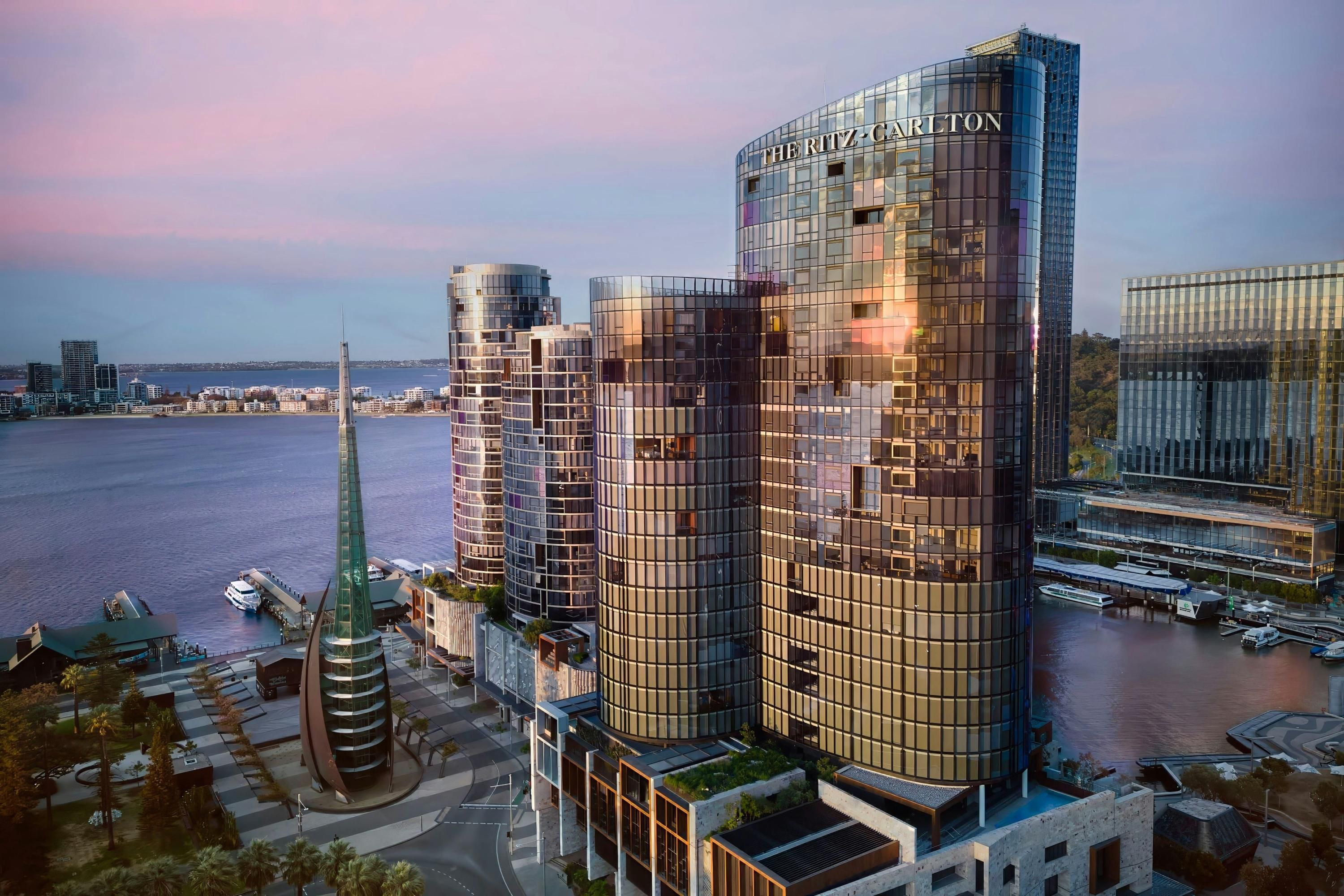 The Ritz-Carlton, Perth waterfront hotel towers over the river at sunset in Perth
