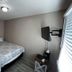 The 409 Bolivar Beach Hotel guest room with queen bed, wall-mounted TV and window blinds in Bolivar Peninsula