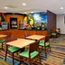 Fairfield Inn & Suites by Marriott Fairfield Napa Valley Area lobby seating area with tables, chairs, and TV