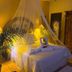 The Mexican Inn in Cabo San Lucas guest room with canopy bed, swan towels, and warm lamps