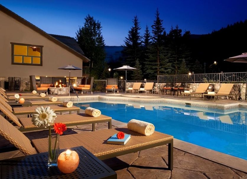 The Osprey at Beaver Creek pool deck at dusk with lounge chairs and mountain backdrop
