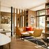 Hotel Eiffel Turenne Paris lounge with wood shelves, tan chairs, orange sofa and city-view windows