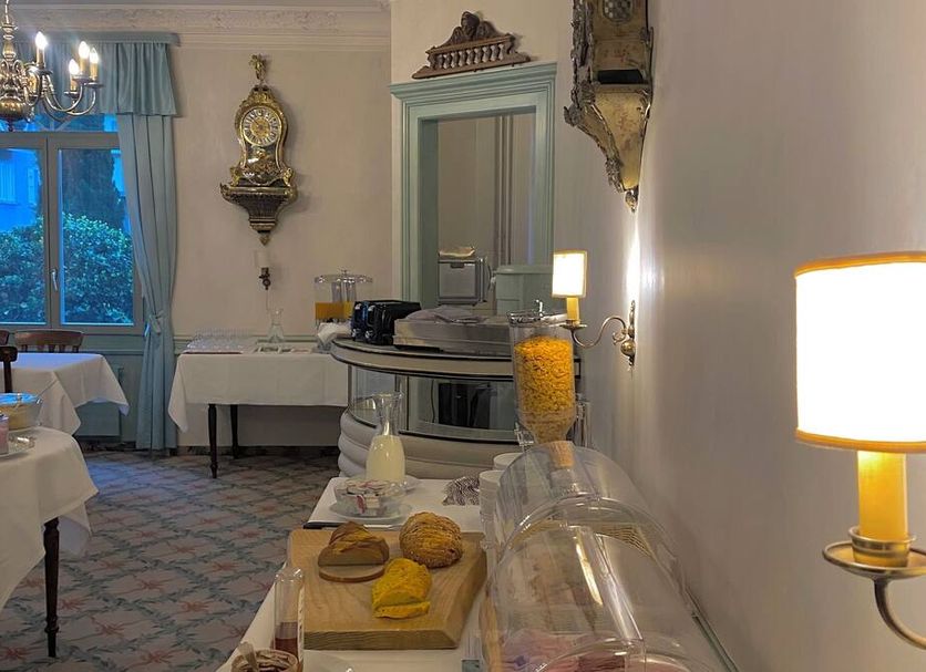 Hotel De La Paix Interlaken breakfast room with buffet table, chandelier, and window view