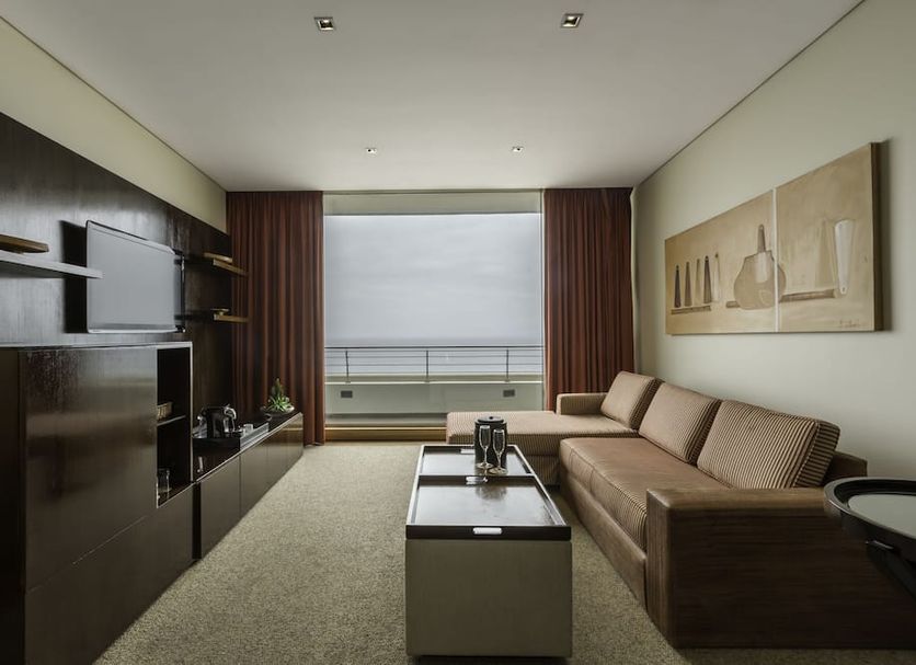Enjoy Coquimbo hotel suite with sofa, TV wall, and ocean-view balcony in Coquimbo