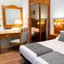 Hotel Horus Zamora in Zamora: a guest room with twin beds, desk, mirror, and warm wood paneling.