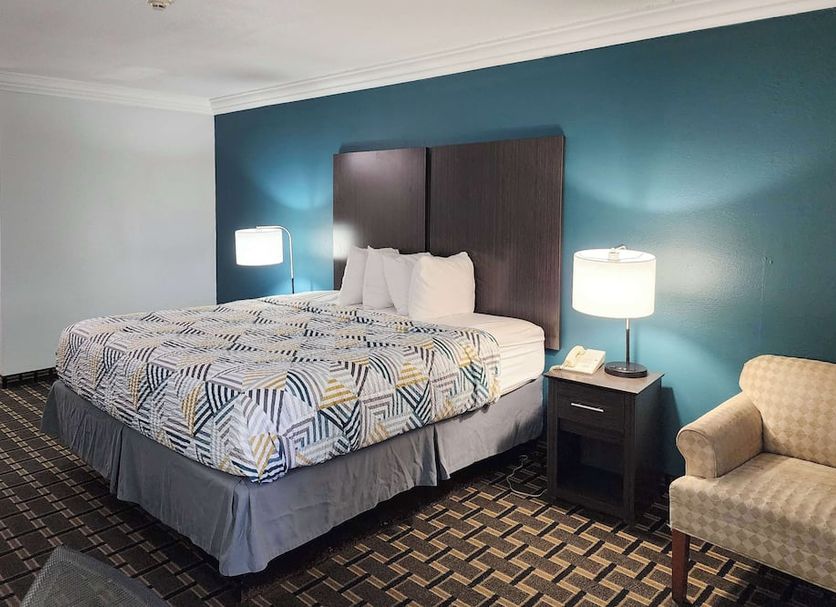 Motel 6 Crowley, La guest room with king bed, lamps, and upholstered chair in Crowley