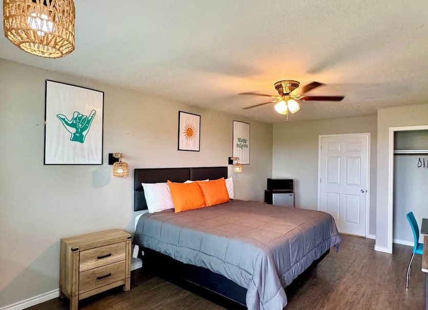 The 409 Bolivar Beach Hotel room with king bed, desk, ceiling fan, and beach-themed wall art in Bolivar Peninsula