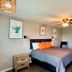 The 409 Bolivar Beach Hotel room with king bed, desk, ceiling fan, and beach-themed wall art in Bolivar Peninsula