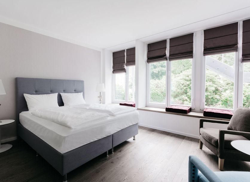 Parkhotel Fritz Am Brunnen in Schwelm guest room with large windows and a bed beside a chair