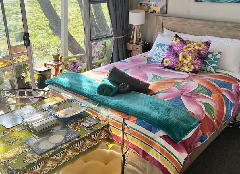 Karikari Lodge in Karikari Peninsula bedroom with colorful bedspread, balcony doors, and garden view