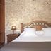 Agroturismo Es Quatre Cantons in Binissalem bedroom with stone wall, wooden headboard, and bedside lamps
