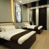 Safir Hotel in Dushanbe guest room with two beds, wood flooring, and dark curtains