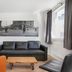 Stay Apartments Einholt Reykjavik apartment lounge with black sofa, orange chair, coffee table and window view