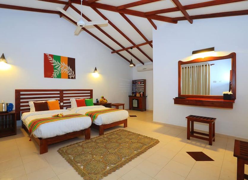 Royal Retreat Sigiriya room with twin beds, high wood-beamed ceiling, wall mirror, and rug