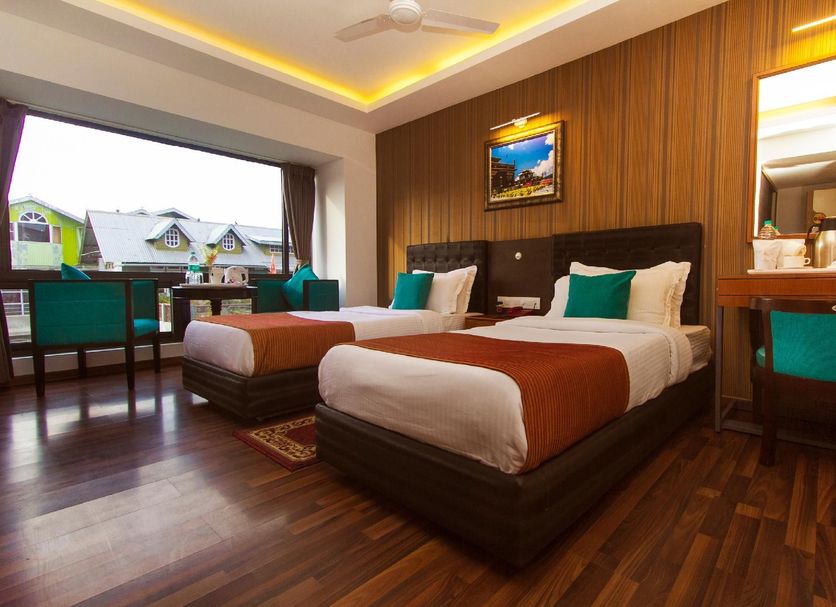 Hotel Jagjeet, Darjeeling guest room with two beds, wood flooring, and large window view