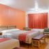 Motel 6 Madras OR room with two beds, orange accent wall, red curtains, and seating area in Madras