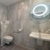 Makom Pereire Paris bathroom with walk-in shower, wall-mounted toilet, sink and illuminated mirror