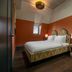 The July - Boat & Co Amsterdam guest room with double bed, bedside lamps and orange walls