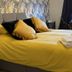 The Leather Bottle in Gravesend: yellow bed with folded towels, dark curtains, and a desk by the window