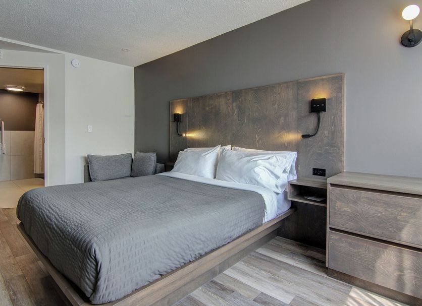 Hotel Motel Normandin Alma in Alma guest room with gray bed, wall lamps, and dresser