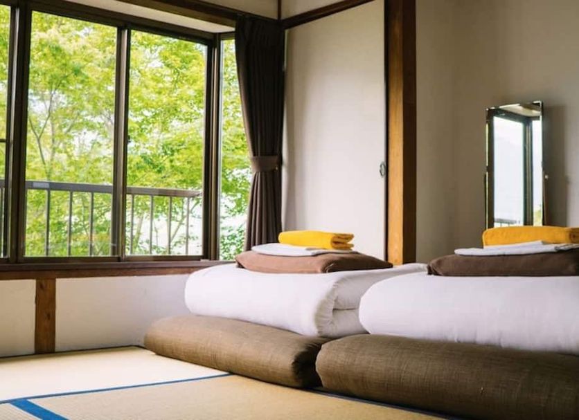 Onsen Guesthouse Hakone Tent room with futon beds and window view of green trees in Hakone