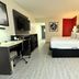 Ramada by Wyndham Tuscaloosa guest room with king bed, desk, wall-mounted TV and light wood flooring