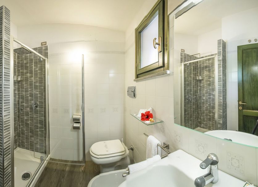 Albaruja Hotel in Costa Rei bathroom with glass shower, wall-mounted toilet and sink vanity