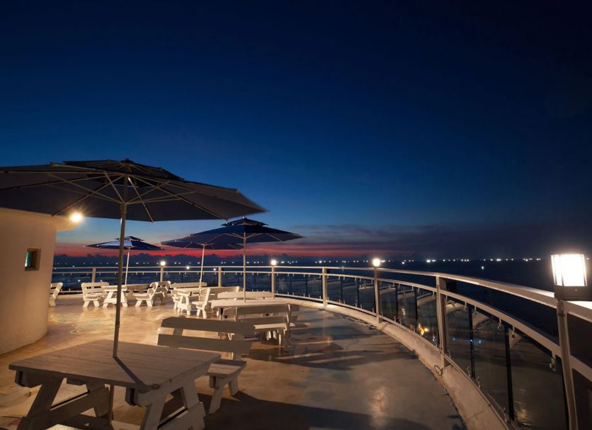 Viewtower Resort in Jeju City rooftop terrace with tables, umbrellas and ocean view at dusk