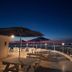 Viewtower Resort in Jeju City rooftop terrace with tables, umbrellas and ocean view at dusk
