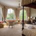 Tre-Ysgawen Hall & Spa in Llangefni bedroom with four-poster bed, chandelier, and sitting area by large windows