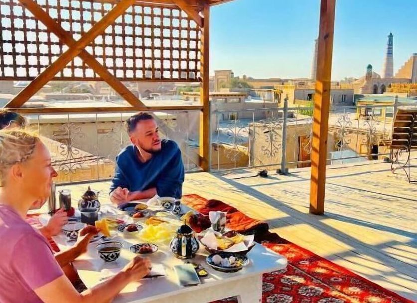 Guests dining on a rooftop terrace at Zukhro Boutique Hotel in Khiva with city views
