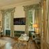 Hotel de la Ville Monza room with chandelier, desk, TV, and large windows overlooking greenery