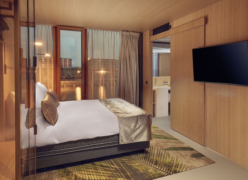 Hotel Jakarta Amsterdam room with bed, balcony doors, and wall-mounted TV in Amsterdam
