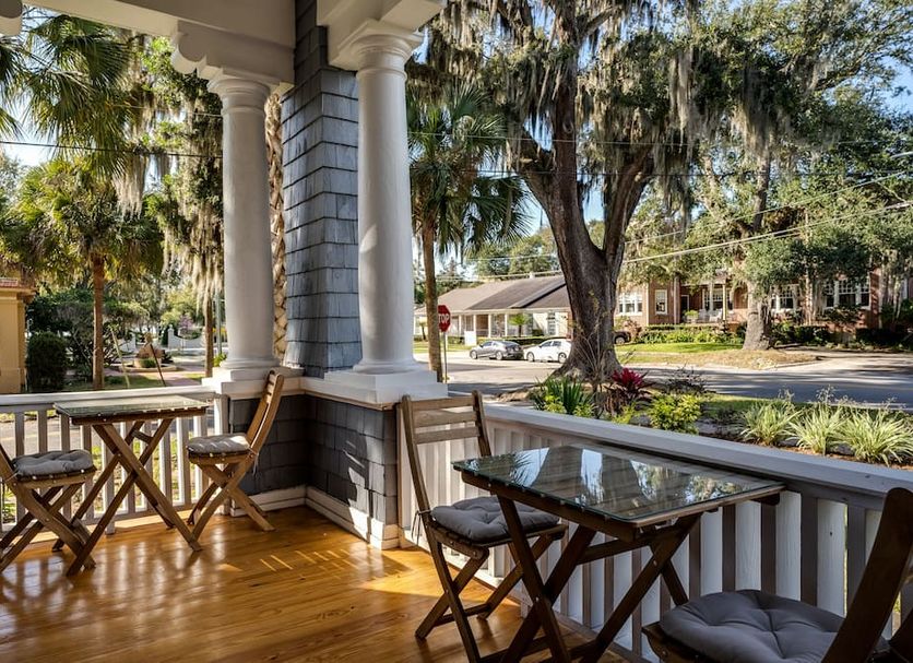 Riverdale Inn in Jacksonville porch with wooden chairs, table, and palm-lined street view