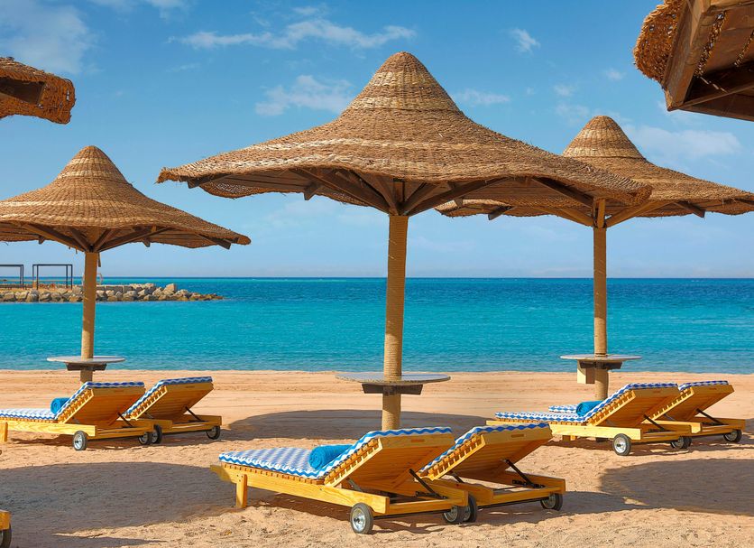 Hilton Hurghada Plaza in Hurghada: beach loungers under straw umbrellas facing turquoise sea