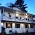 Lakeside Bed & Breakfast in Florence, two-story white inn with holiday garlands and lit balcony