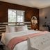 J Patrick Inn in Cambria guest room with a bed, sitting area by the window, and rustic wood-paneled wall