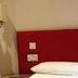 The Bull And Bush Hotel Kingston room with red headboard, bed, lamp, and window in Kingston upon Thames