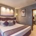 Grand Residency Hotel & Serviced Apartments in Mumbai bedroom with tufted bed and adjoining dining area