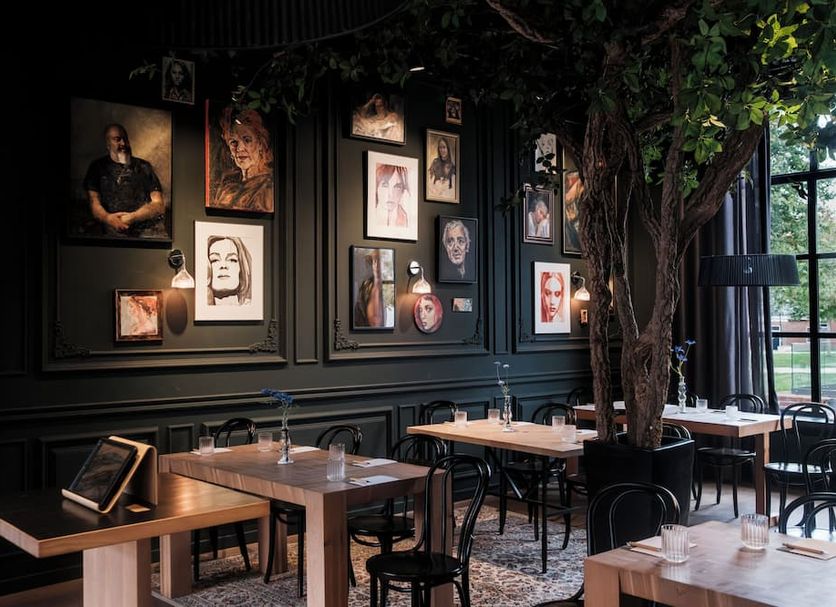 Hotel Abdij Dokkum in Dokkum, dark-paneled restaurant with portrait wall and tree centerpiece
