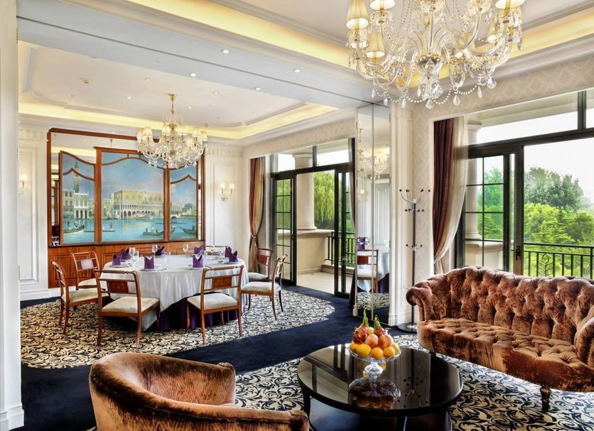 Chateau Star River Beijing dining room with chandelier, plush sofa, and balcony garden view