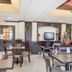 Holiday Inn Express & Suites Byram lobby seating area with tables, chairs, TV, and decorative plants