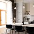 Maison Place Royale by Luxury In Transit in Montreal: modern kitchen with island, black chairs, and pendant lights