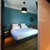Hotel Rossi, Sartène: guest room with teal accent wall, double bed and glass shower area