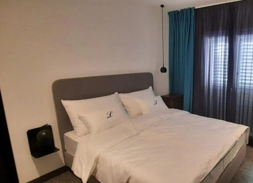 Vila Lili in Rovinj guest room with bed, wall-mounted TV, desk and teal curtains