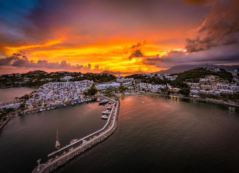 Sunset harbor view at Las Hadas by Brisas in Manzanillo, with marina, boats and hillside buildings.